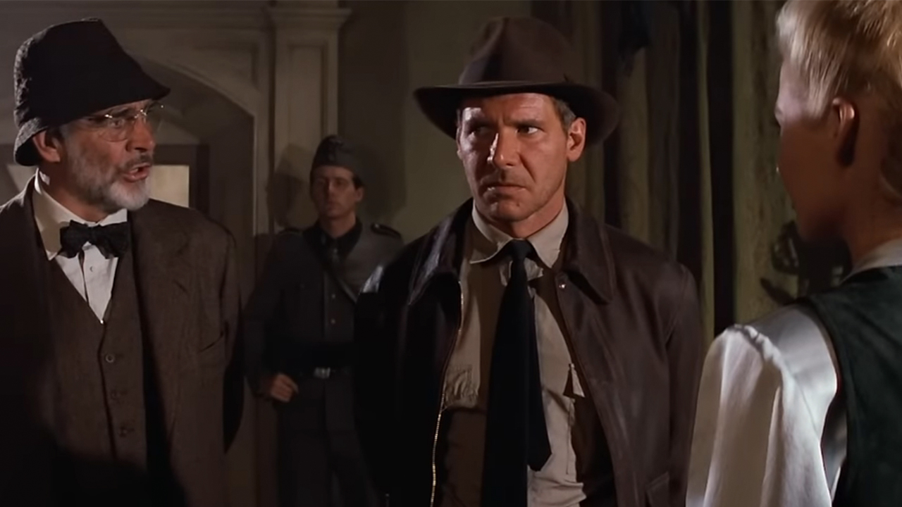 Sean Connery in a suit, looking at Harrison Ford in The Last Crusade