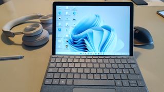 Beste laptoper for barn: En Microsoft Surface Go 3 står åpen på en bordplate sammen med en digital penn, mus og hodetelefoner.