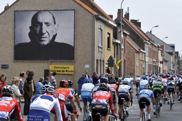 The peloton passes a larger than life photo of legendary Belgian pro Briek Schotte.