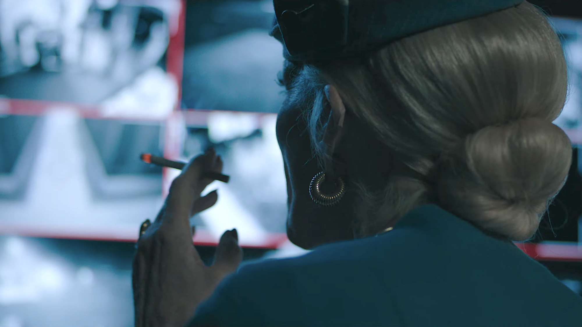 Allison Janney's character smoking a cigarette and watching a monitor of security footage in The Dog Stars