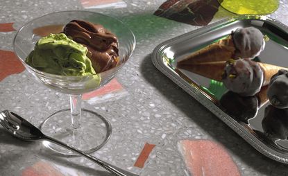 mint and chocolate gelato in glass cup on black and white marble countertop 