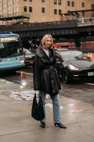 woman wearing leather jacket, white shirt, jeans, and boots