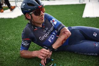 Laurence Pithie looks on, with his face caked in mud, and injuries sustained on his elbow after crashing at the 2024 Paris-Roubaix where he finished 7th on the day