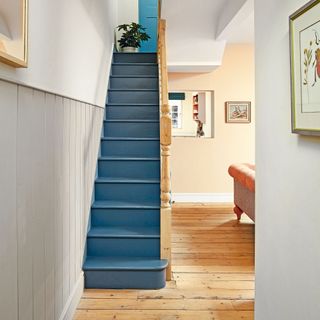 Blue painted stairs in hallway with light grey painted tongue and groove wall panelling