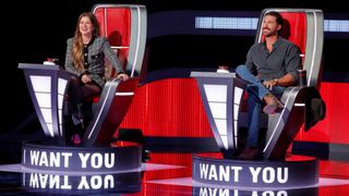 The Voice judges Kelly Clarkson and Riley Green sitting in their red chairs in Season 30.