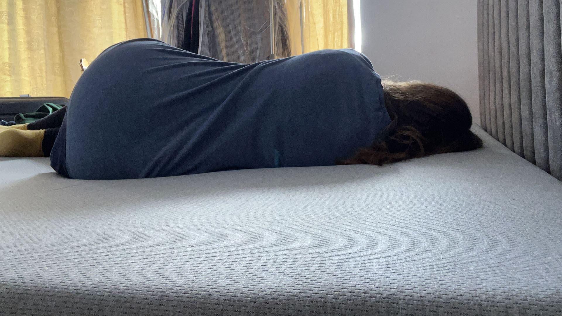 Reviewer lying on her side on the Zoma Hybrid mattress