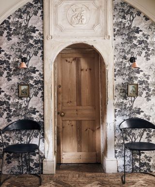 Classical entrance hall with monochrome botanical leafy wallpaper and a pair of chairs