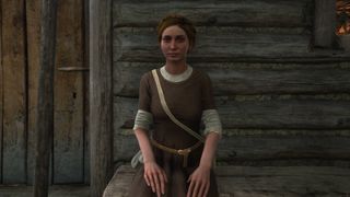 Klara sits outside her hut.