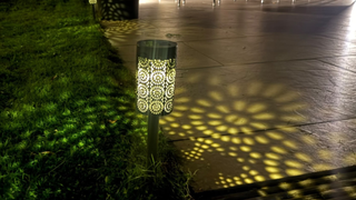 moroccan style stake solar light in grass with the pattern reflected on grass and patio