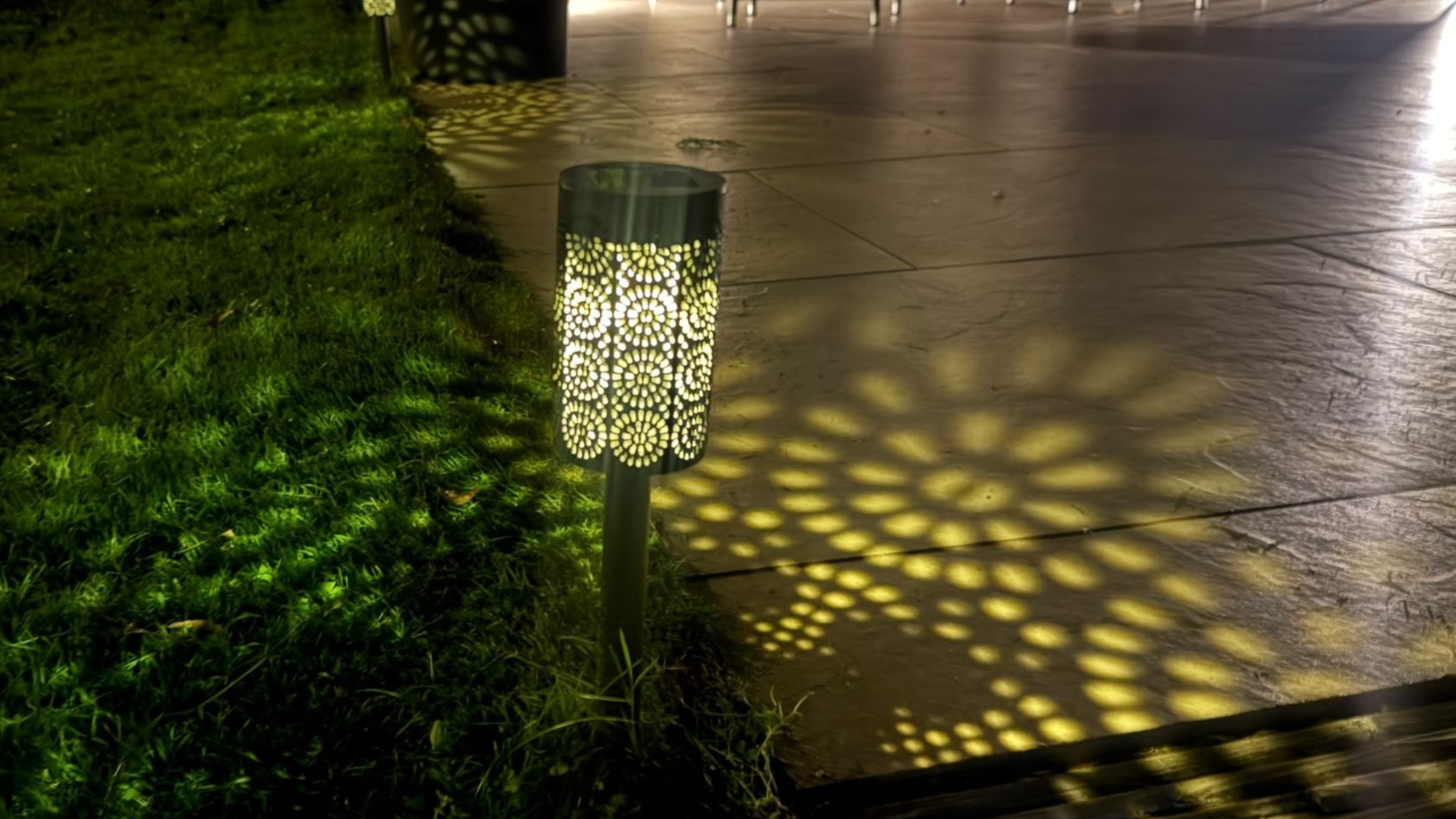 moroccan style stake solar light in grass with the pattern reflected on grass and patio