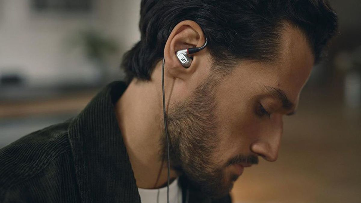 A young man looking downwards, seen from the side, wearing the Sennheiser IE900 earbuds.