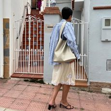 model wears blue button-down and white lace skirt and kitten heels