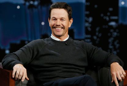 Mark Wahlberg sits on a couch.