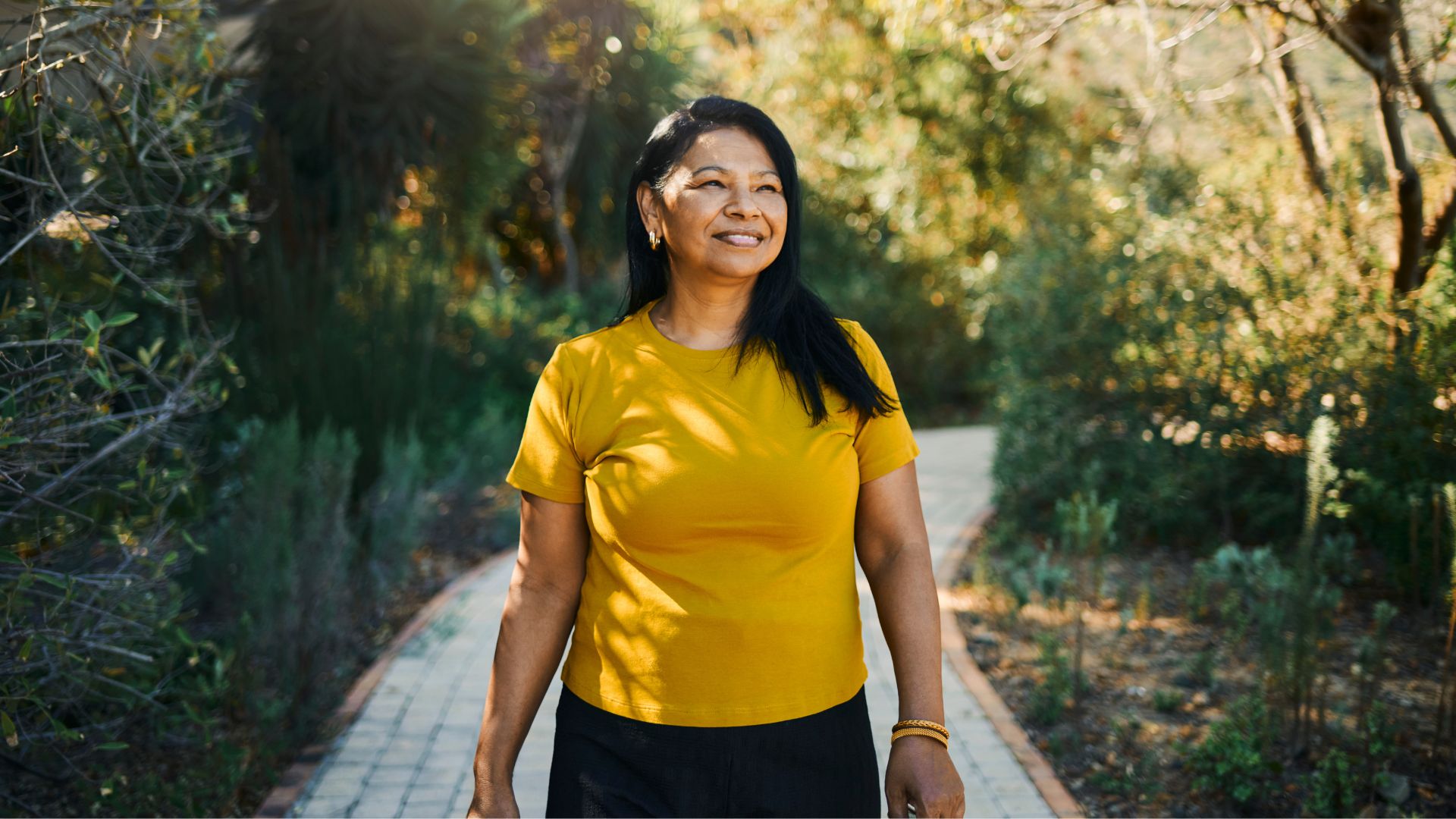 Woman walking along path in sunshine