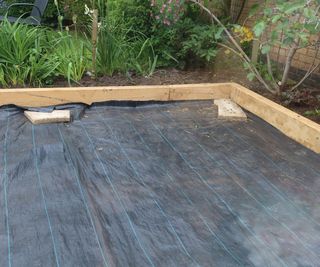 A weedproof membrane laid before installing a paving area in a garden