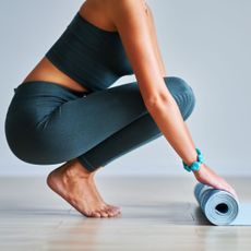 Does Pilates at home work? A woman rolling out a workout mat