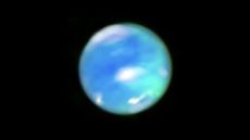 A blurry image of Neptune with cyan-colored cloudy shapes on its surface