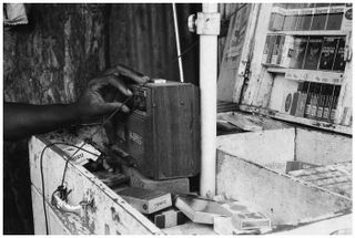 Black and white photo of a hand adjusting the dial on a wooden radio