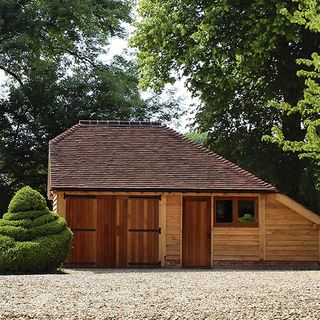 wooden garage with garden area with tree
