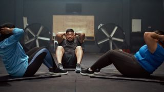 Three people doing sit-ups during their workout in the gym