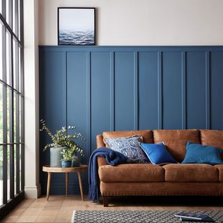 living area with blue wall and brown sofa and wooden floor