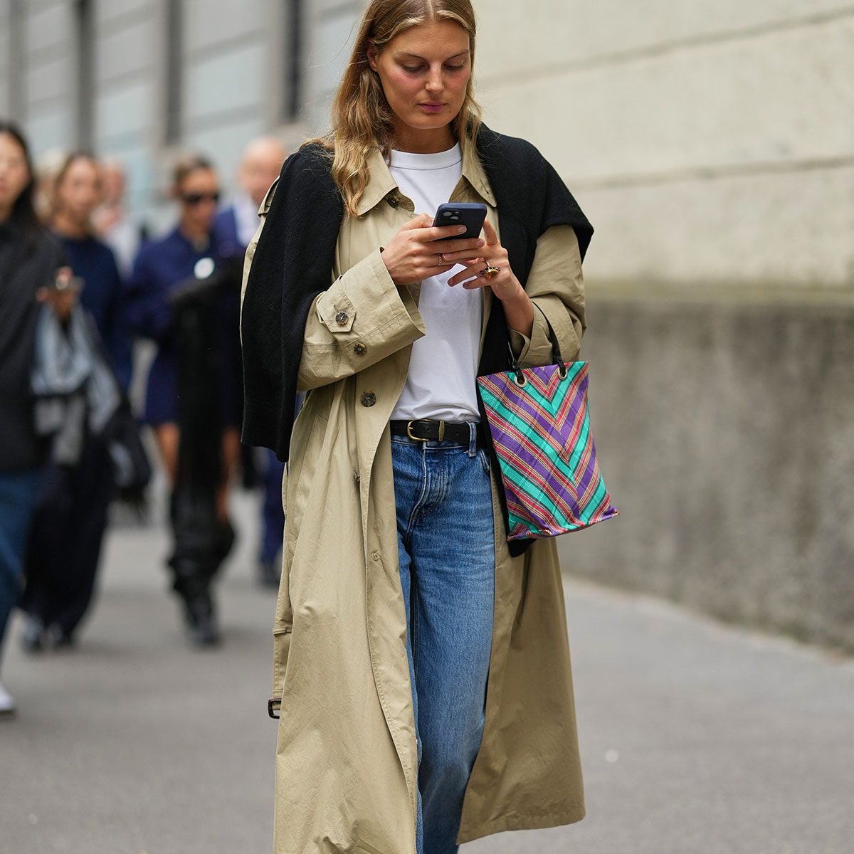 Woman in a trench coat looking at a phone
