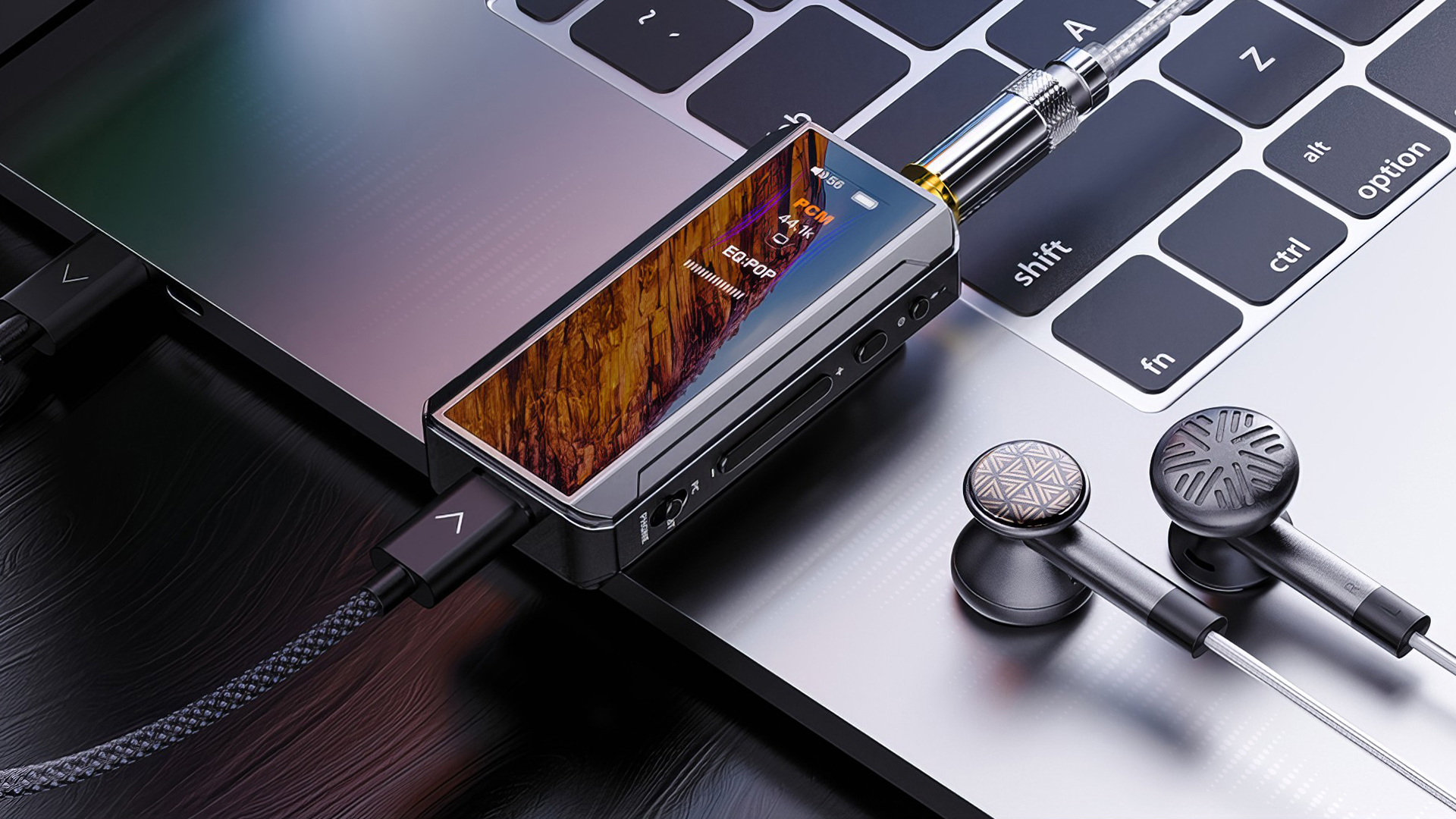 FiiO BTR13 headphone DAC laying on a MacBook with earbuds nearby