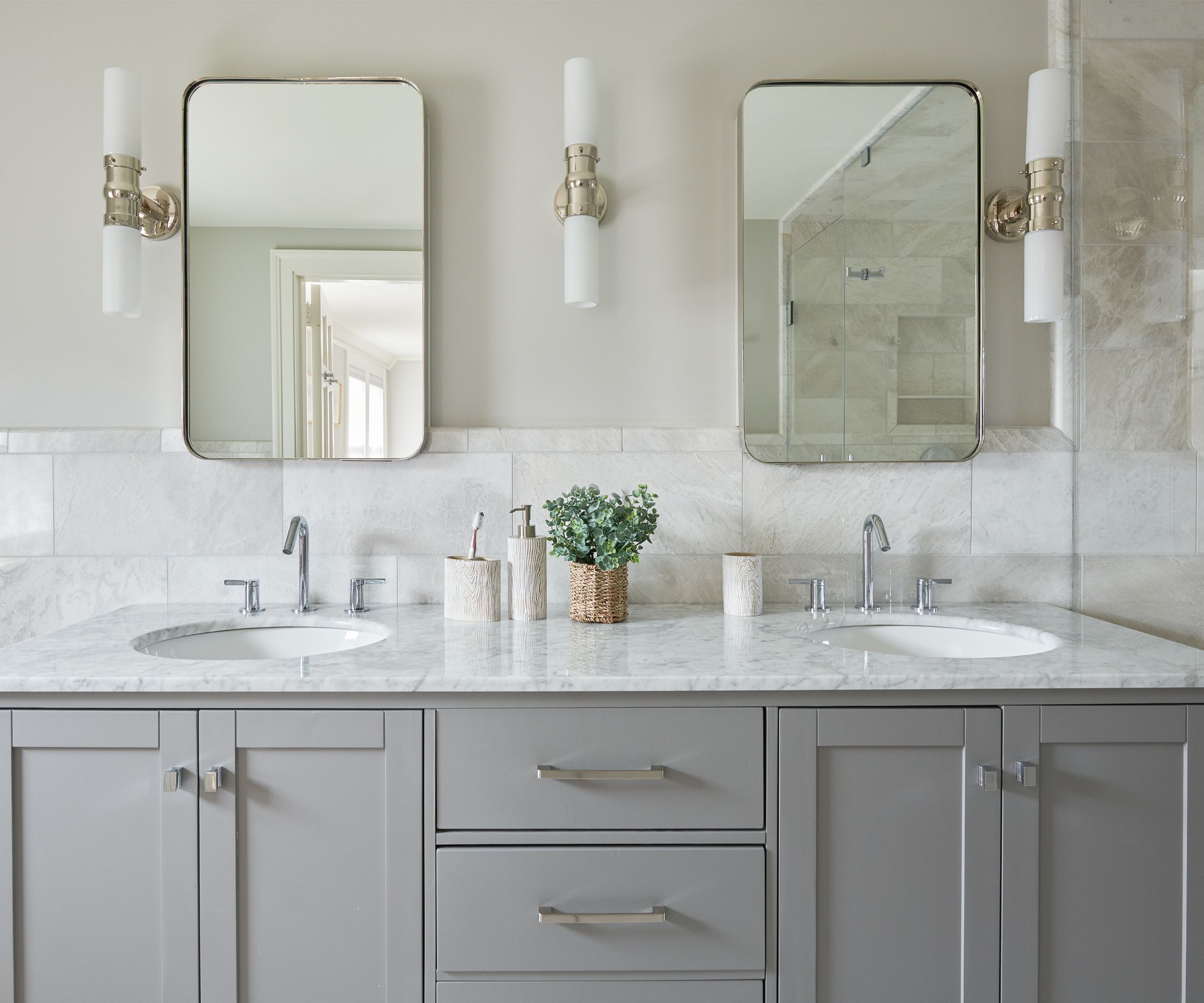 A neutral bathroom with a gray vanity and aesthetic pots to store toothbrushes