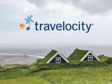 The travelocity logo above two eco-cabins with grass roofs on the coast