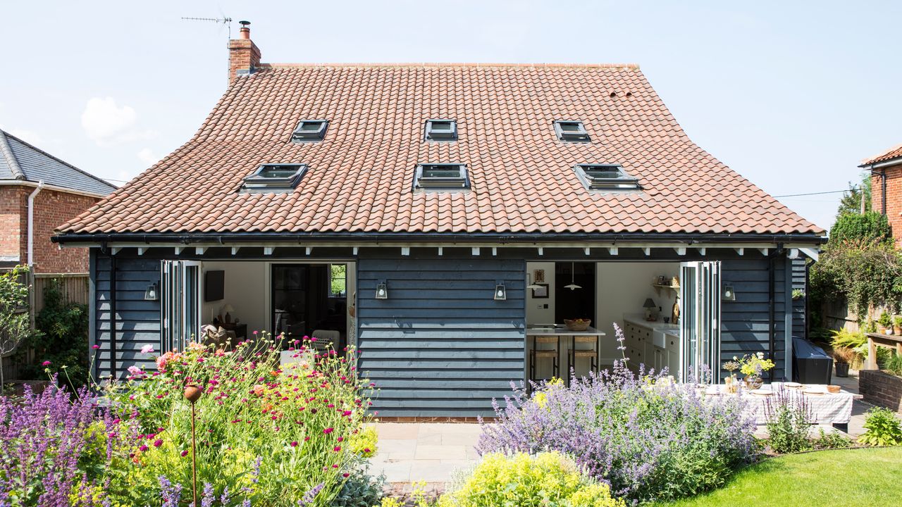 country cottage exterior rear view back garden with wooden exterior cladding and plenty of planting and lavender