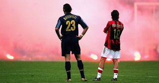 Marco Materazzi of Inter Milan and Rui Costa of AC Milan look on as Inter fans shower the pitch with flares during the UEFA Champions League quarter-final second leg between AC Milan and Inter Milan at the San Siro Stadium on April 12, 2005 in Milan, Italy.