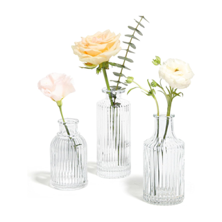 three small fluted glass flower vases holding flowers 