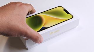 Apple iPhone 14 yellow unboxing box angled hand