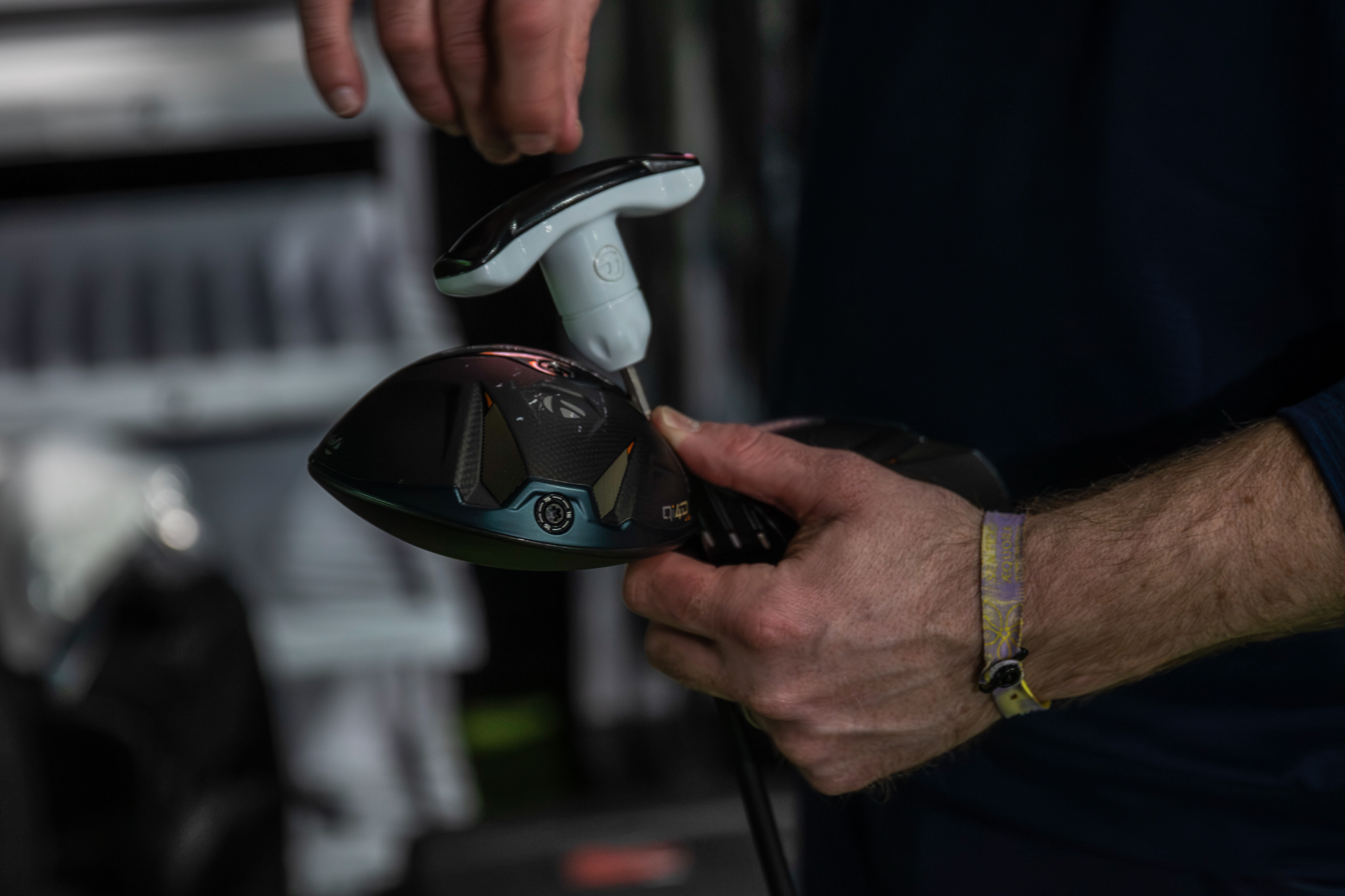 A golf fitter adjusts the head of a TaylorMade driver