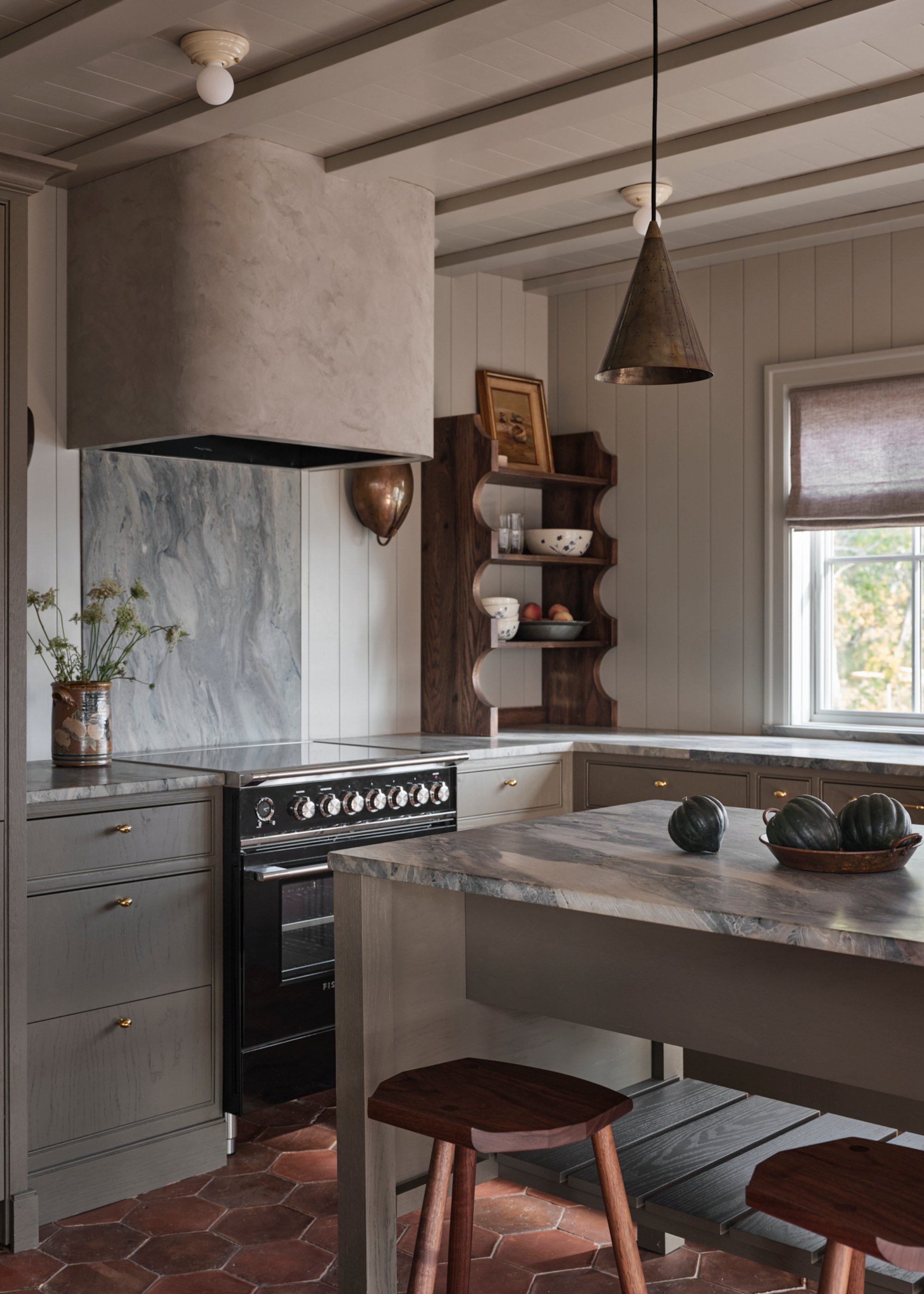 An all grey kitchen brought to life with lots of textural finishes such as wood, marble countertop, cement, metal lighting, terracotta tiles