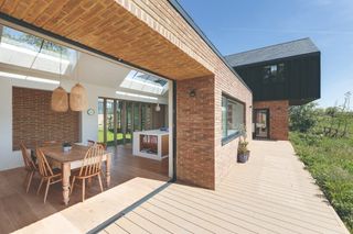 A modern home with open bifold doors leading out to a composite decking 