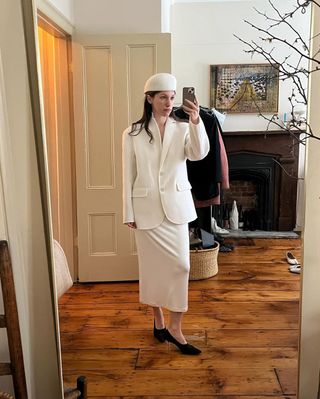 Laura Reilly wearing a cream The Row drivers cap with a matching blazer and skirt.