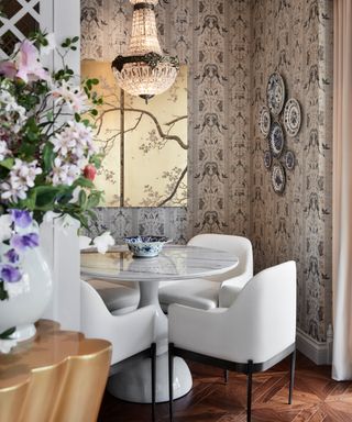 Maximalist dining space with wallpaper white table and chairs, plates on wall,