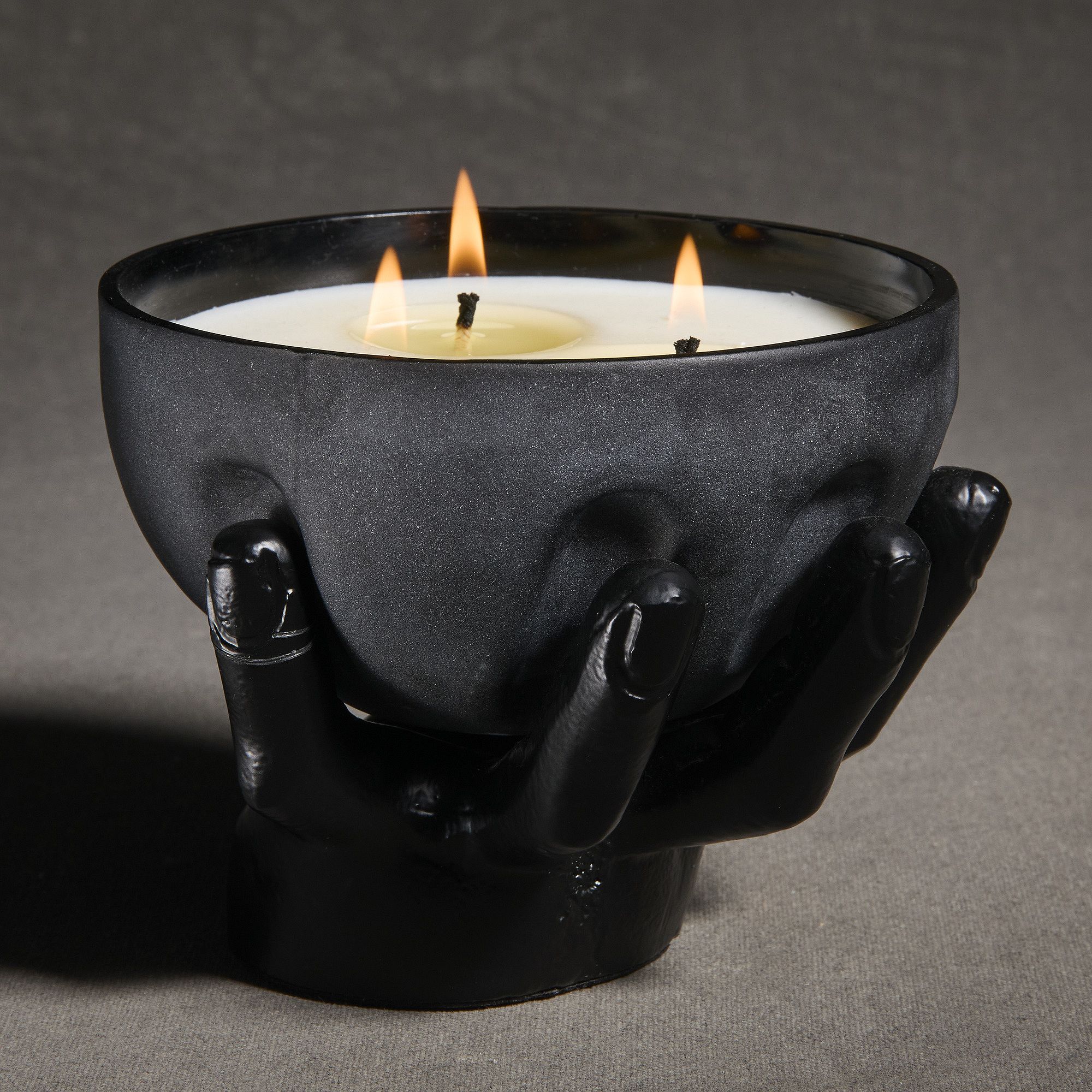 a black candle being held by a hand statue