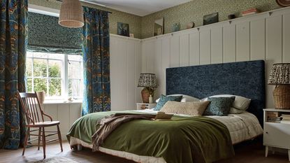 green patterned roman blind over window above kitchen sink and panelled blue walls