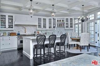 A white kitchen with coffered ceilings, shaker cabinetry, an a dining table