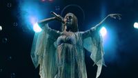 Anne Hathaway singing on stage in flowing outfit as Mother Mary 