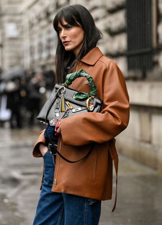 Leia Sfez is seen wearing a brown leather Hermes jacket, blue jeans and Hermes black bag outside the Hermes show during the Womenswear Fall/Winter 2024/2025 as part of Paris Fashion Week on March 02, 2024