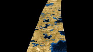 an orange strip of a moon's surface is dotted with large dark blue lakes in a false-color image