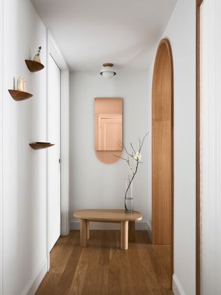 a contemporary hallway with a mirror shelves and table