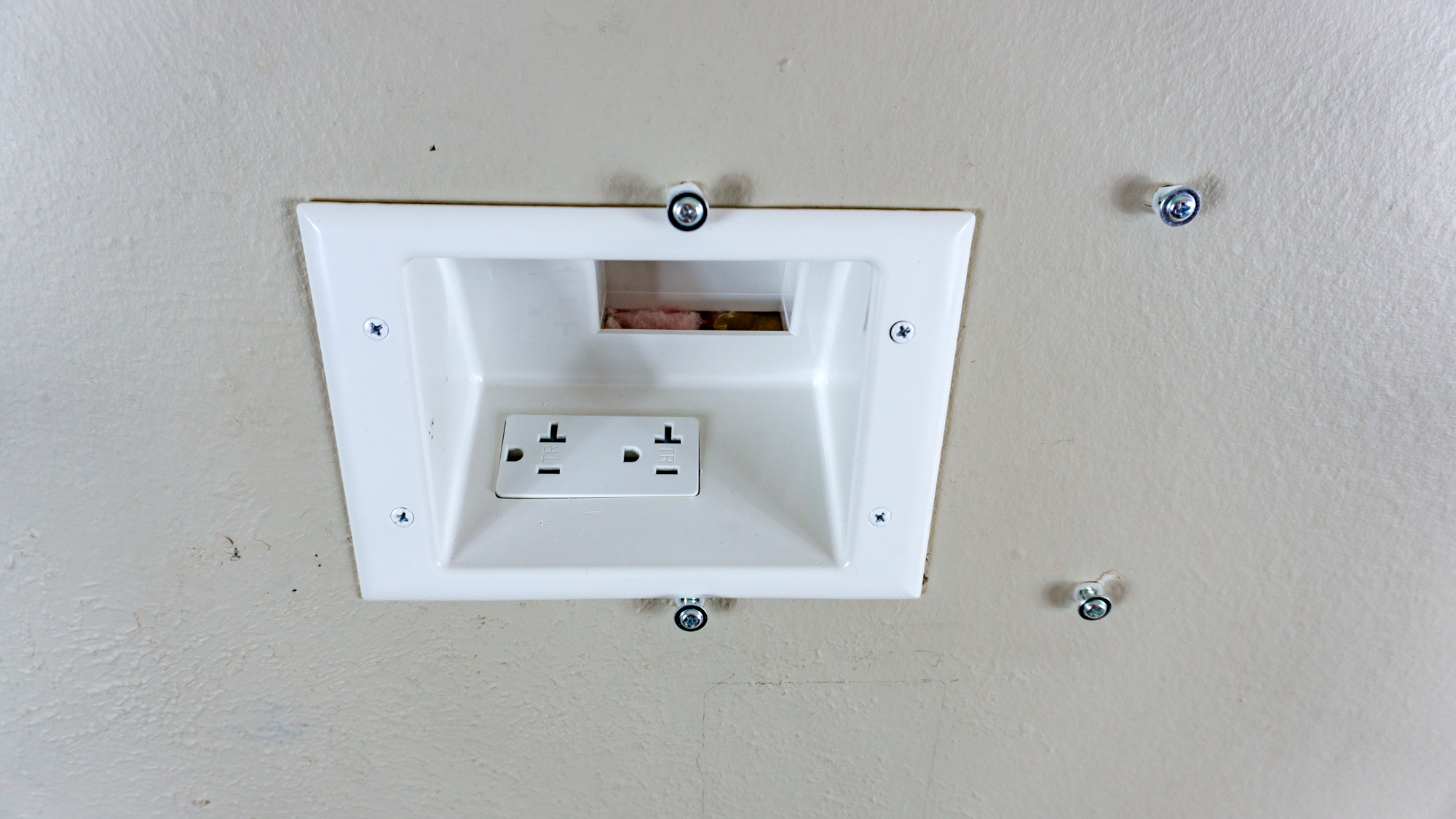A recessed wall outlet installed on a wall to hide the power cable for a digital wall calendar