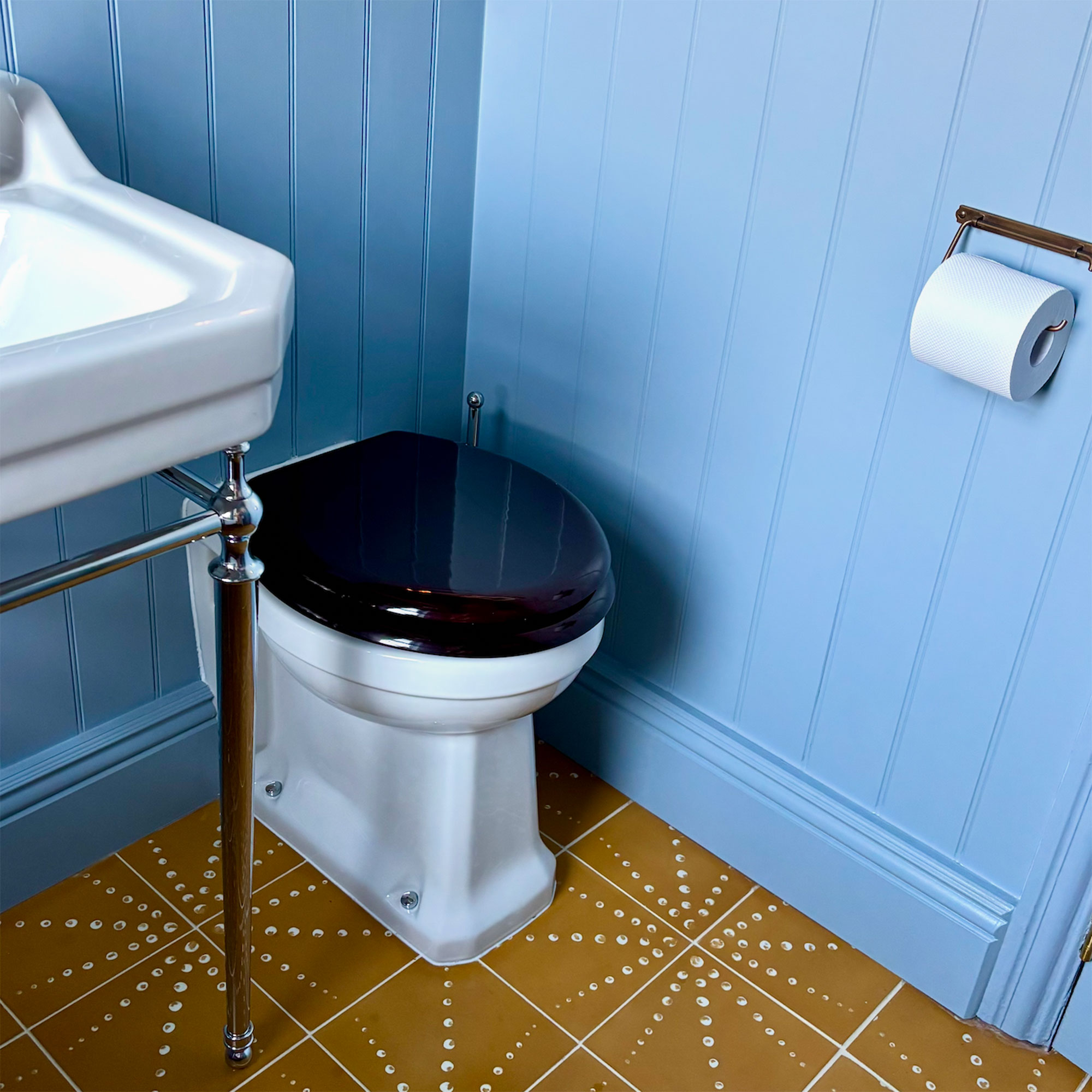 Loo in blue panelled bathroom with mustard yellow patterned tiles