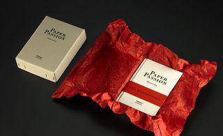 A book "Paper Passion" unwrapped from red tissue paper and lying beside the closed gift box