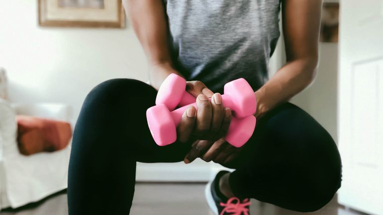 woman holding pink dumbbells