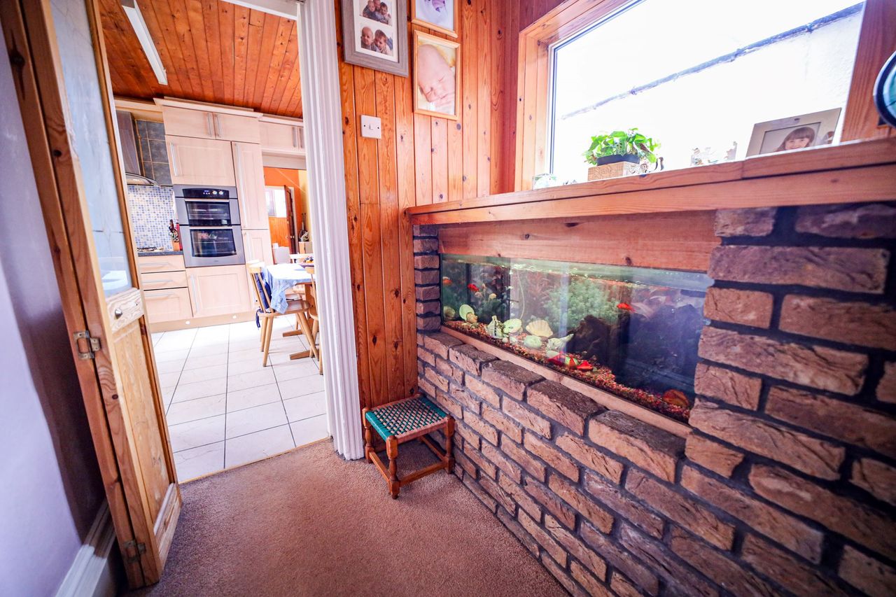 A brick wall with a fish tank built into it, which lies next to the kitchen